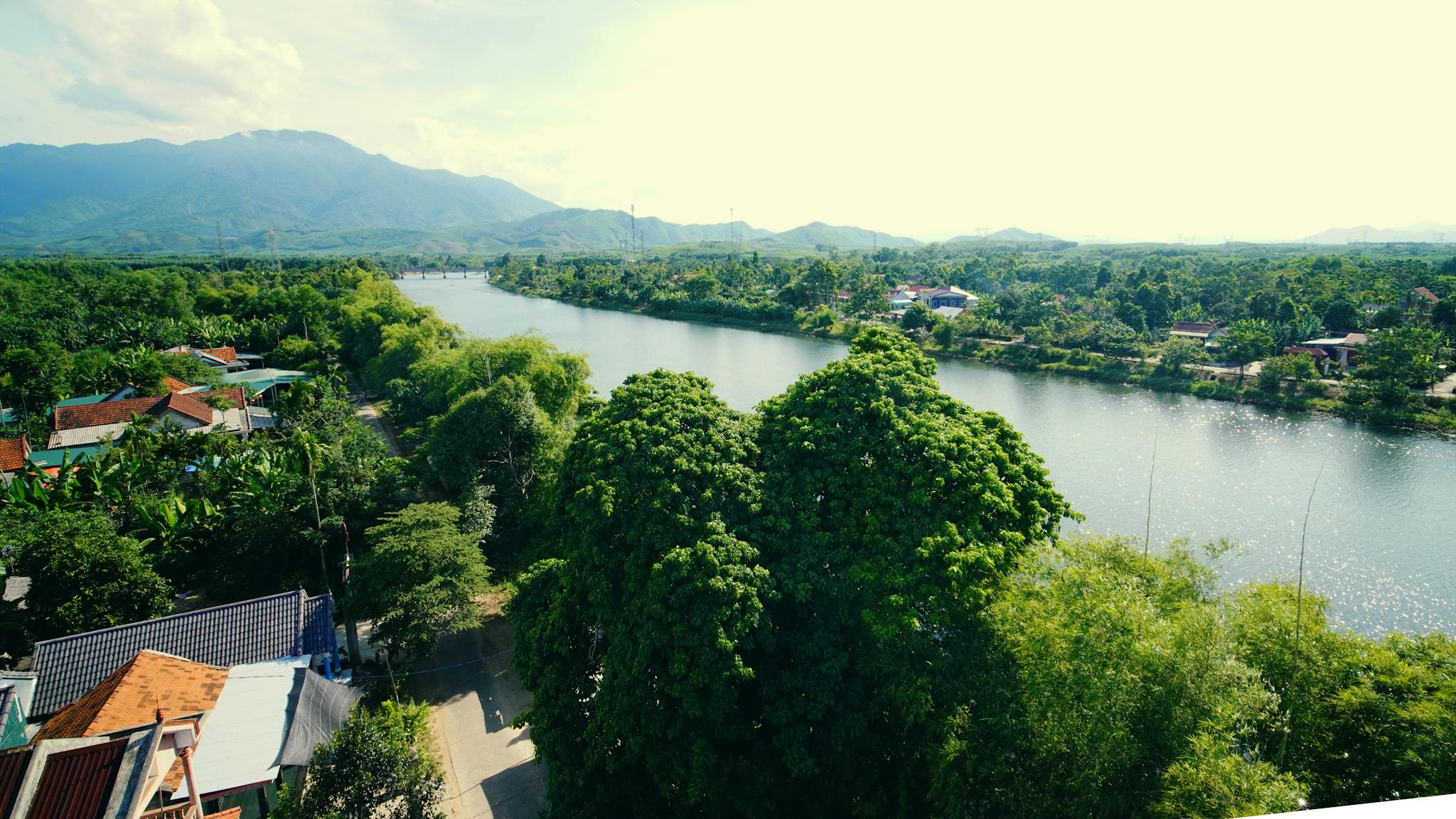A picturesque view of a river flowing through lush greenery under a mountain backdrop.